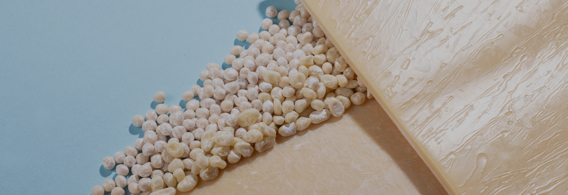 Pile of pale puffed cereal beads spilling from a white chocolate bar onto a blue and tan background.