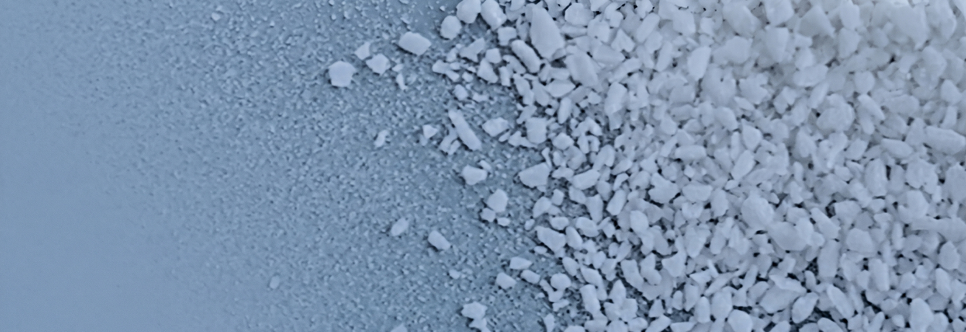 Macro shot showing fine powder transitioning into larger white gravel along a diagonal, highlighting texture contrast and granule sizes.